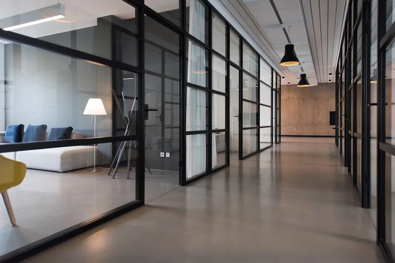 Un couloir de bureaux vitrés dans la lumière du matin